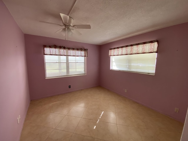 tiled empty room with ceiling fan and a textured ceiling