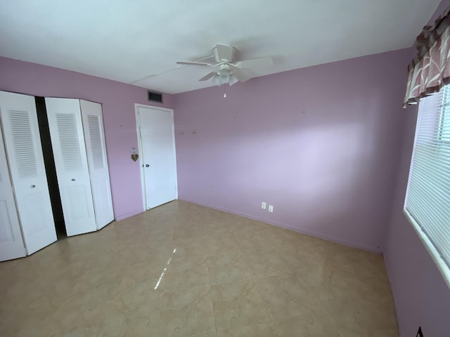 unfurnished bedroom featuring ceiling fan and two closets