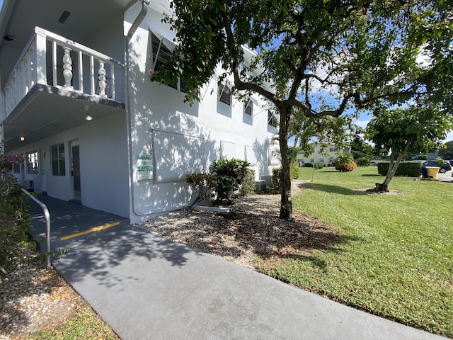 95 Cambridge E Unit 95, West Palm Beach, FL 33417 - view of side of home featuring stucco siding, a lawn, and a balcony