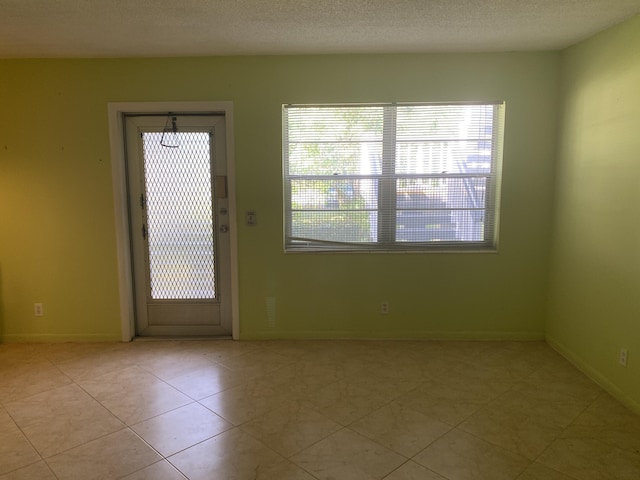 95 Cambridge E Unit 95, West Palm Beach, FL 33417 - unfurnished room with plenty of natural light, baseboards, light tile patterned flooring, and a textured ceiling