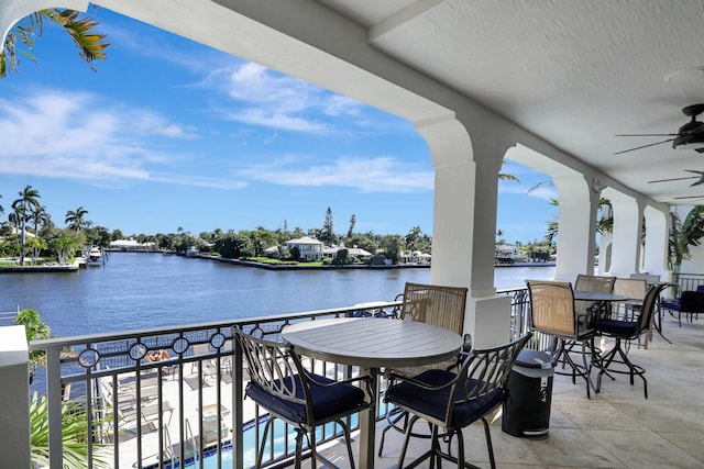 view of patio featuring ceiling fan, a water view, and a balcony