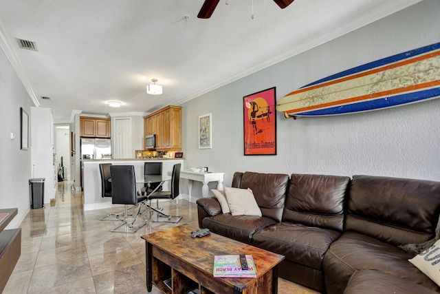 living room featuring ceiling fan, a textured ceiling, and ornamental molding