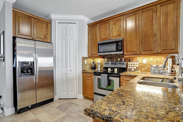 kitchen with sink, stainless steel appliances, backsplash, dark stone countertops, and ornamental molding