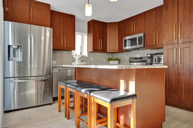 kitchen with tasteful backsplash, light hardwood / wood-style flooring, stainless steel appliances, and decorative light fixtures