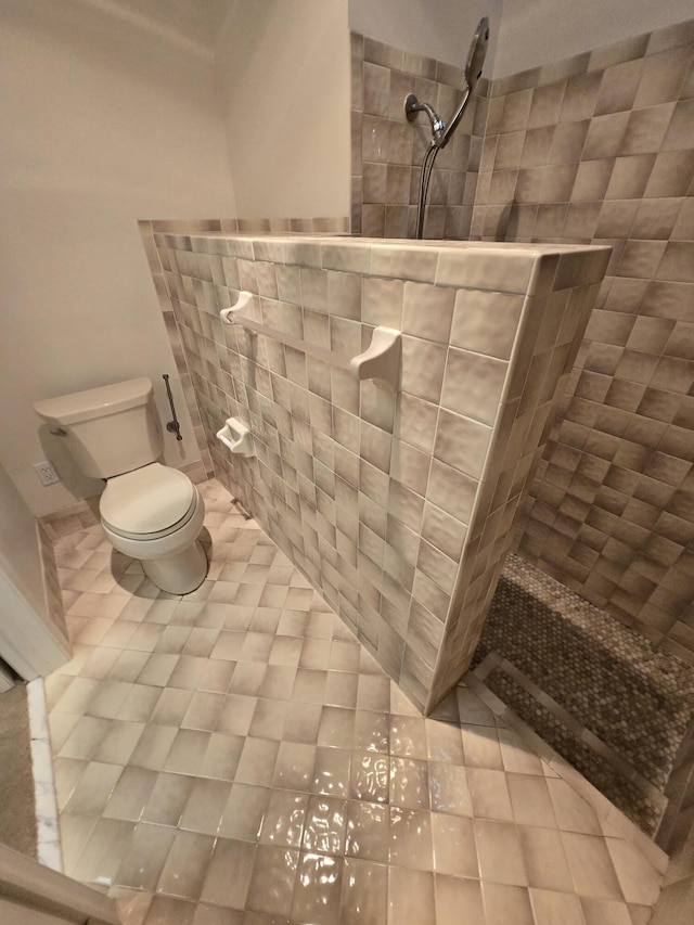 bathroom with toilet, tile patterned flooring, and tiled shower