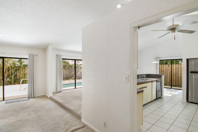 kitchen featuring light carpet, stainless steel dishwasher, vaulted ceiling, ceiling fan, and white cabinetry