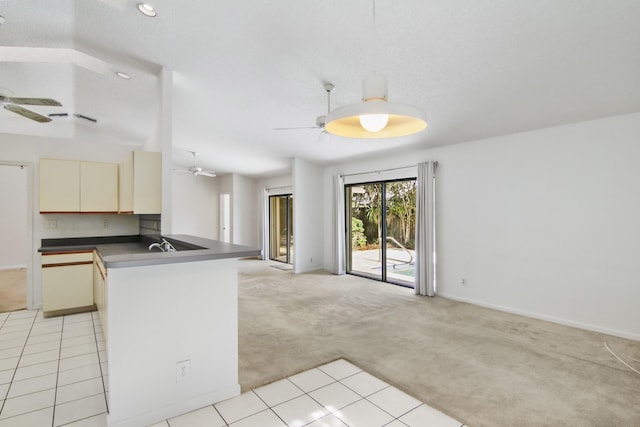 kitchen with kitchen peninsula, cream cabinets, light colored carpet, and decorative backsplash