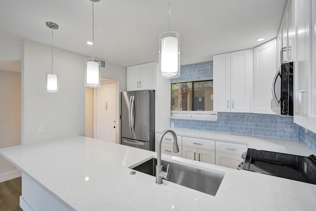 kitchen with freestanding refrigerator, a sink, tasteful backsplash, a peninsula, and pendant lighting