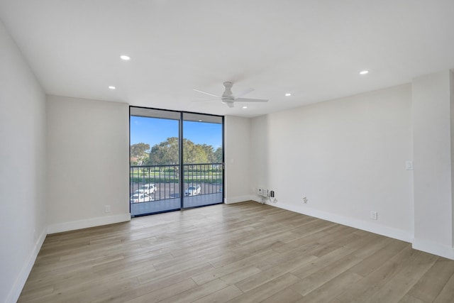 spare room featuring a wall of windows, light hardwood / wood-style floors, and ceiling fan