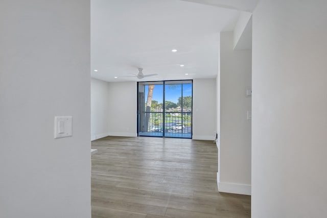 unfurnished room featuring floor to ceiling windows, light hardwood / wood-style floors, and ceiling fan