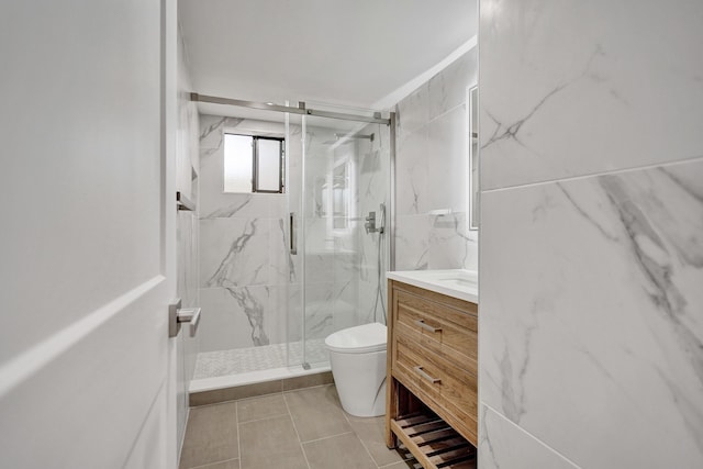 bathroom featuring vanity, toilet, a shower with door, and tile walls