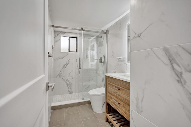 bathroom featuring tile patterned floors, vanity, a shower with door, tile walls, and toilet