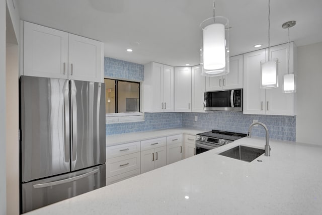 kitchen with sink, white cabinetry, hanging light fixtures, appliances with stainless steel finishes, and backsplash