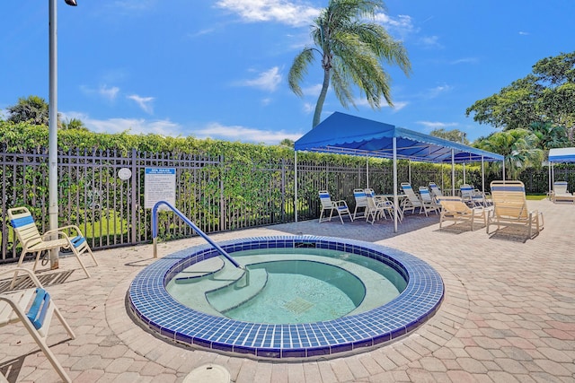 view of swimming pool featuring fence, a hot tub, and a patio