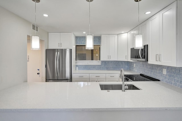 kitchen with stainless steel appliances, a sink, backsplash, pendant lighting, and light stone countertops