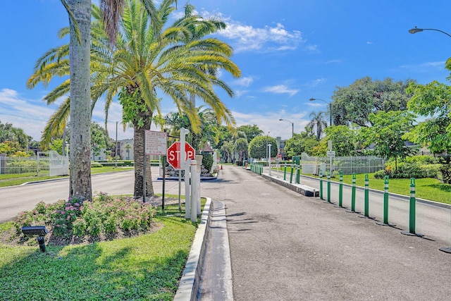 view of asphalt street with street lights, traffic signs, and curbs