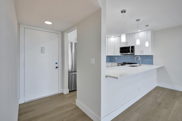 kitchen with stainless steel appliances, light countertops, light wood-style flooring, decorative backsplash, and recessed lighting
