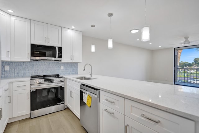 kitchen featuring sink, stainless steel appliances, light hardwood / wood-style flooring, pendant lighting, and white cabinets