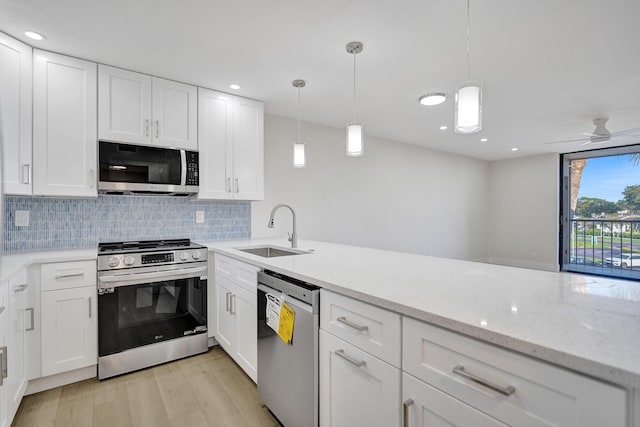 kitchen featuring appliances with stainless steel finishes, a sink, backsplash, light wood finished floors, and white cabinets