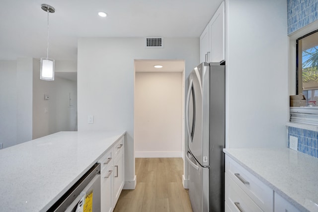 kitchen featuring light stone countertops, decorative light fixtures, white cabinetry, light hardwood / wood-style floors, and stainless steel refrigerator