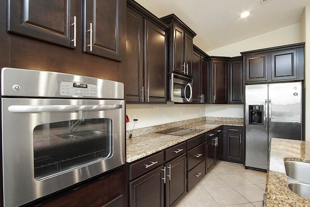 kitchen featuring appliances with stainless steel finishes, light stone counters, dark brown cabinets, light tile patterned floors, and lofted ceiling