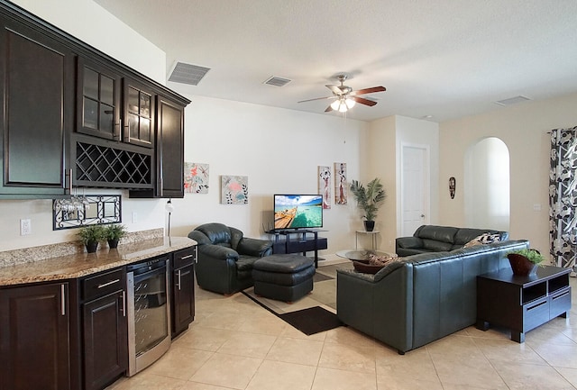 tiled living room featuring ceiling fan, a textured ceiling, and beverage cooler