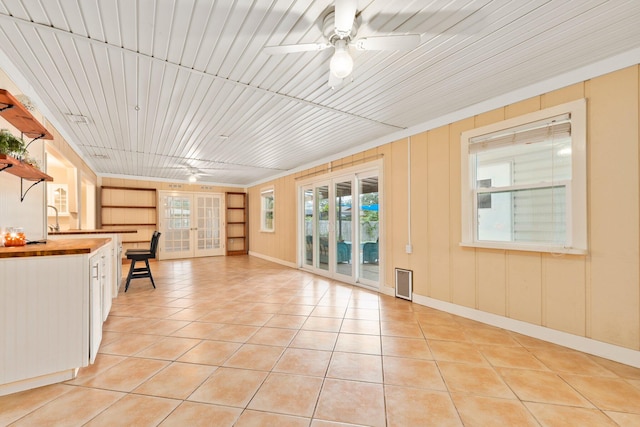 unfurnished living room with ceiling fan, wooden ceiling, and light tile patterned flooring