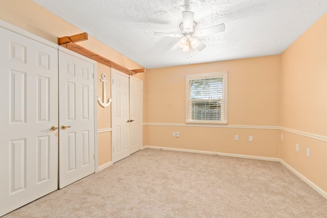 unfurnished bedroom with ceiling fan, light carpet, and a textured ceiling