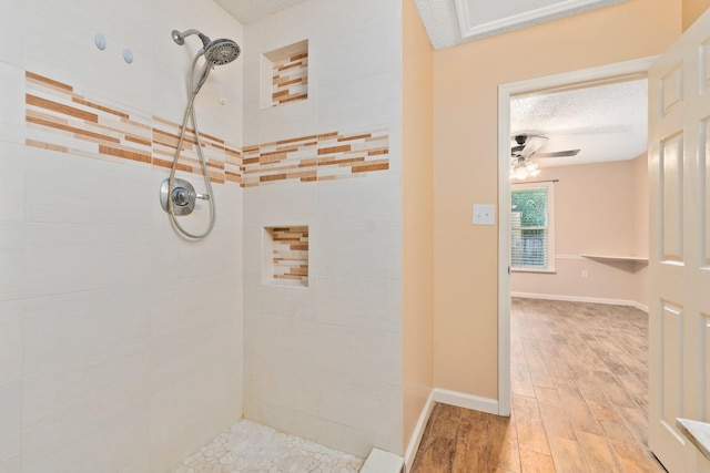 bathroom with hardwood / wood-style floors, tiled shower, ceiling fan, and a textured ceiling