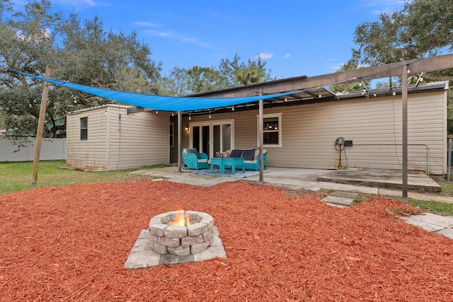 rear view of property featuring an outdoor living space with a fire pit and a patio