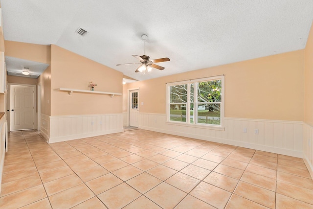 tiled empty room featuring a textured ceiling, vaulted ceiling, and ceiling fan