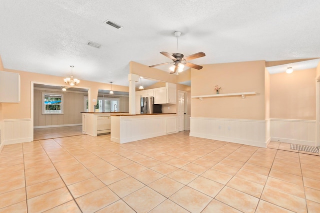 interior space with ceiling fan with notable chandelier, light tile patterned floors, and a textured ceiling