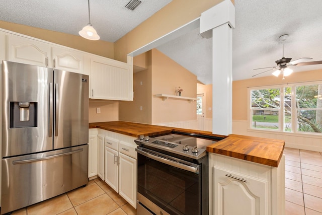 kitchen with hanging light fixtures, wooden counters, a textured ceiling, and appliances with stainless steel finishes