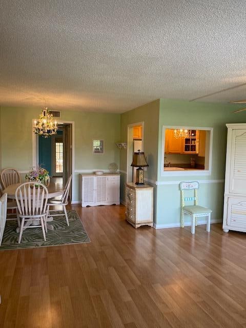 unfurnished dining area featuring hardwood / wood-style floors, a textured ceiling, and an inviting chandelier