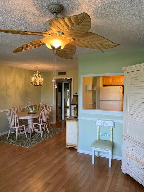 interior space with ceiling fan with notable chandelier, a textured ceiling, white fridge, and dark hardwood / wood-style floors