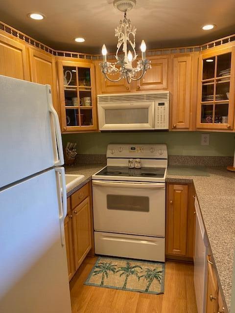 kitchen featuring white appliances, an inviting chandelier, light hardwood / wood-style flooring, and hanging light fixtures