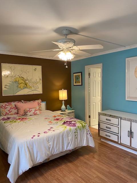 bedroom with hardwood / wood-style flooring, ceiling fan, and crown molding