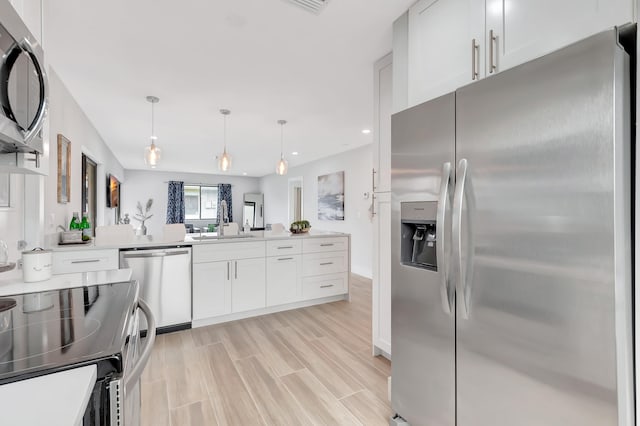 kitchen with sink, stainless steel appliances, pendant lighting, white cabinets, and light wood-type flooring