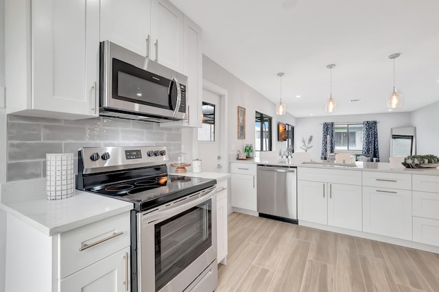 kitchen with decorative light fixtures, backsplash, stainless steel appliances, and white cabinetry