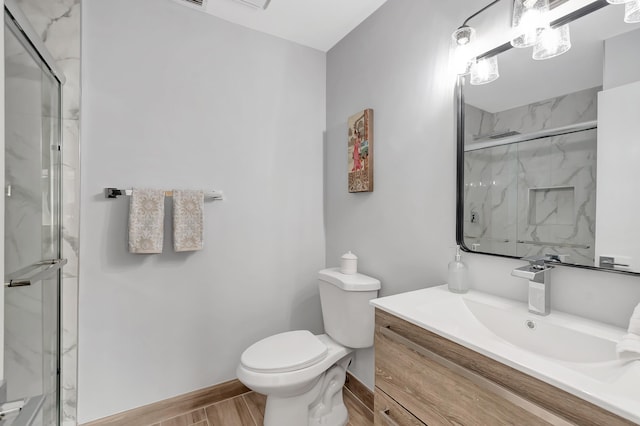 bathroom featuring vanity, a shower with shower door, and toilet