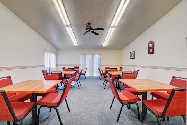 carpeted dining area featuring ceiling fan, lofted ceiling, and a textured ceiling