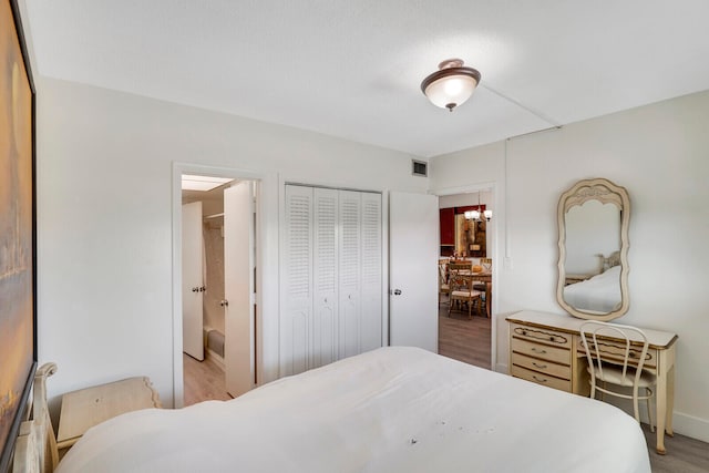 bedroom featuring a closet, an inviting chandelier, and light hardwood / wood-style flooring