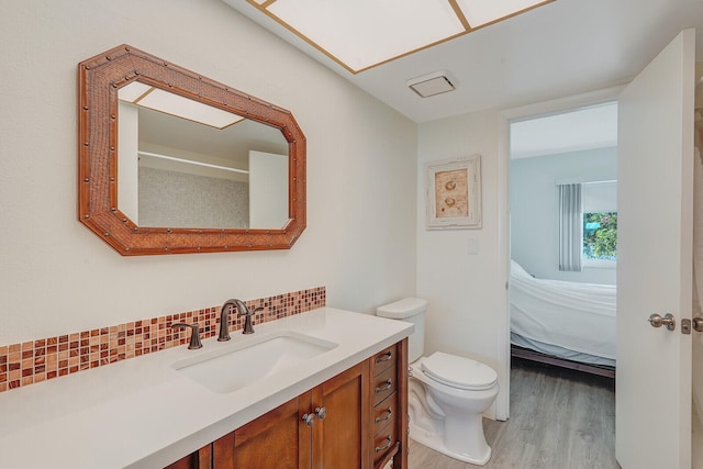 bathroom with hardwood / wood-style floors, vanity, toilet, and decorative backsplash