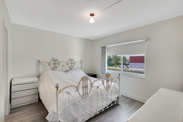 bedroom with a textured ceiling and dark hardwood / wood-style flooring