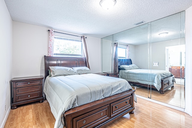 bedroom featuring a textured ceiling and light hardwood / wood-style flooring