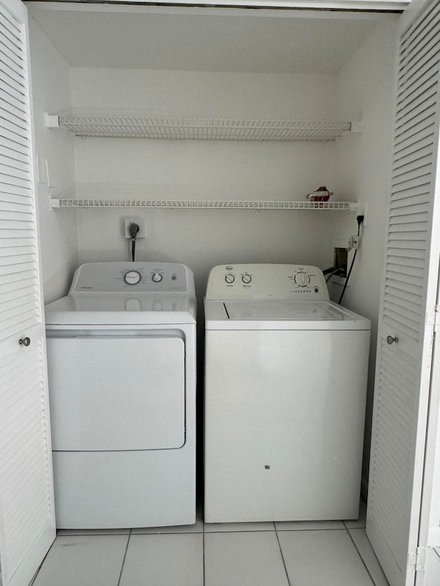 laundry room with light tile patterned floors and washer and clothes dryer