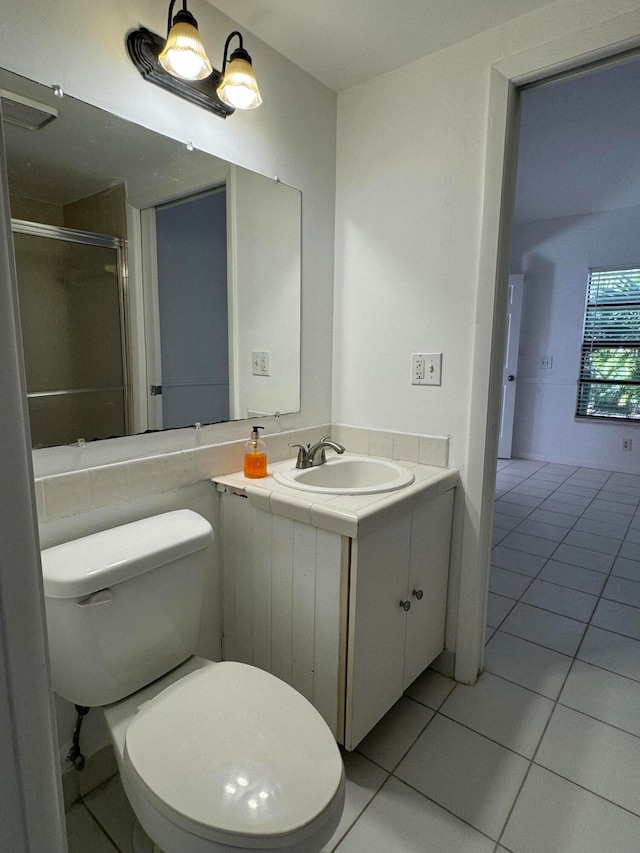 bathroom featuring tile patterned flooring, vanity, toilet, and a shower with shower door