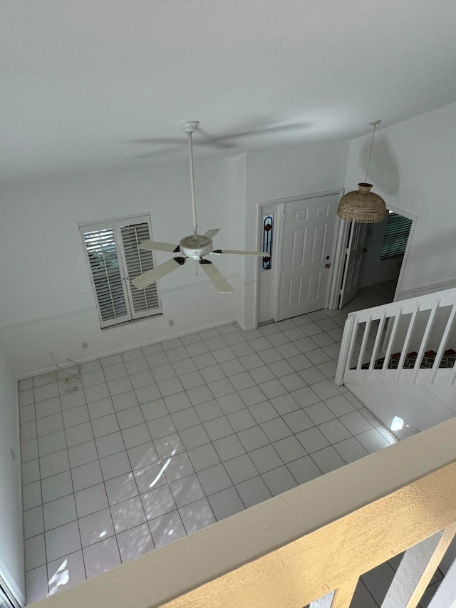 unfurnished living room with ceiling fan, light tile patterned floors, and vaulted ceiling