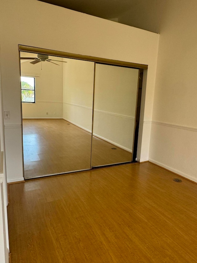 unfurnished bedroom featuring ceiling fan, a closet, and wood-type flooring