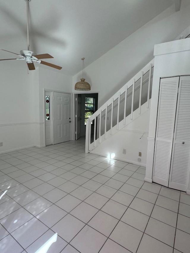 foyer featuring ceiling fan, light tile patterned floors, and high vaulted ceiling